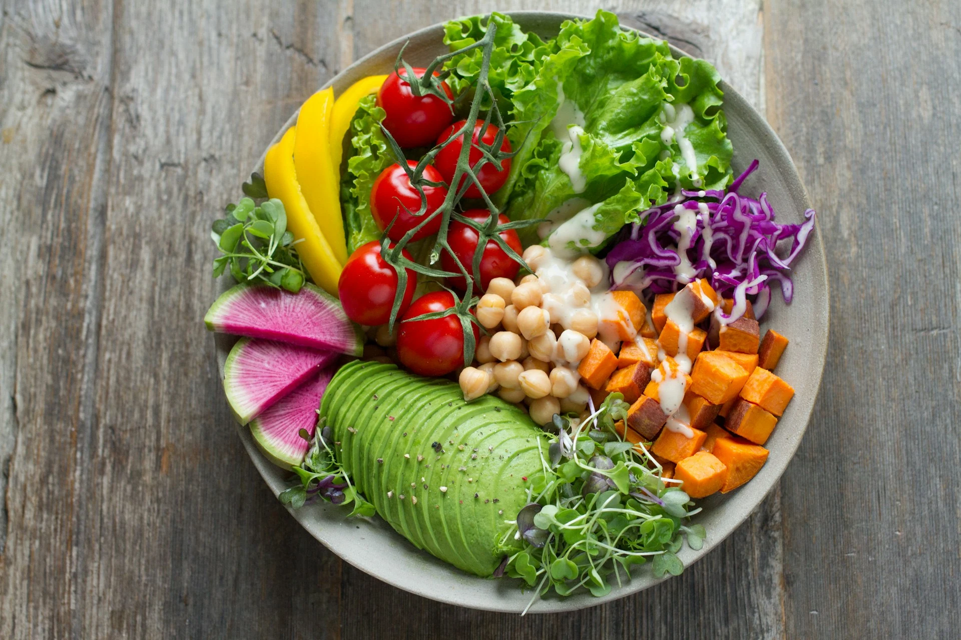 A bowl of chickpeas, avocado, sweet potato, tomatoes and leafy vegetables