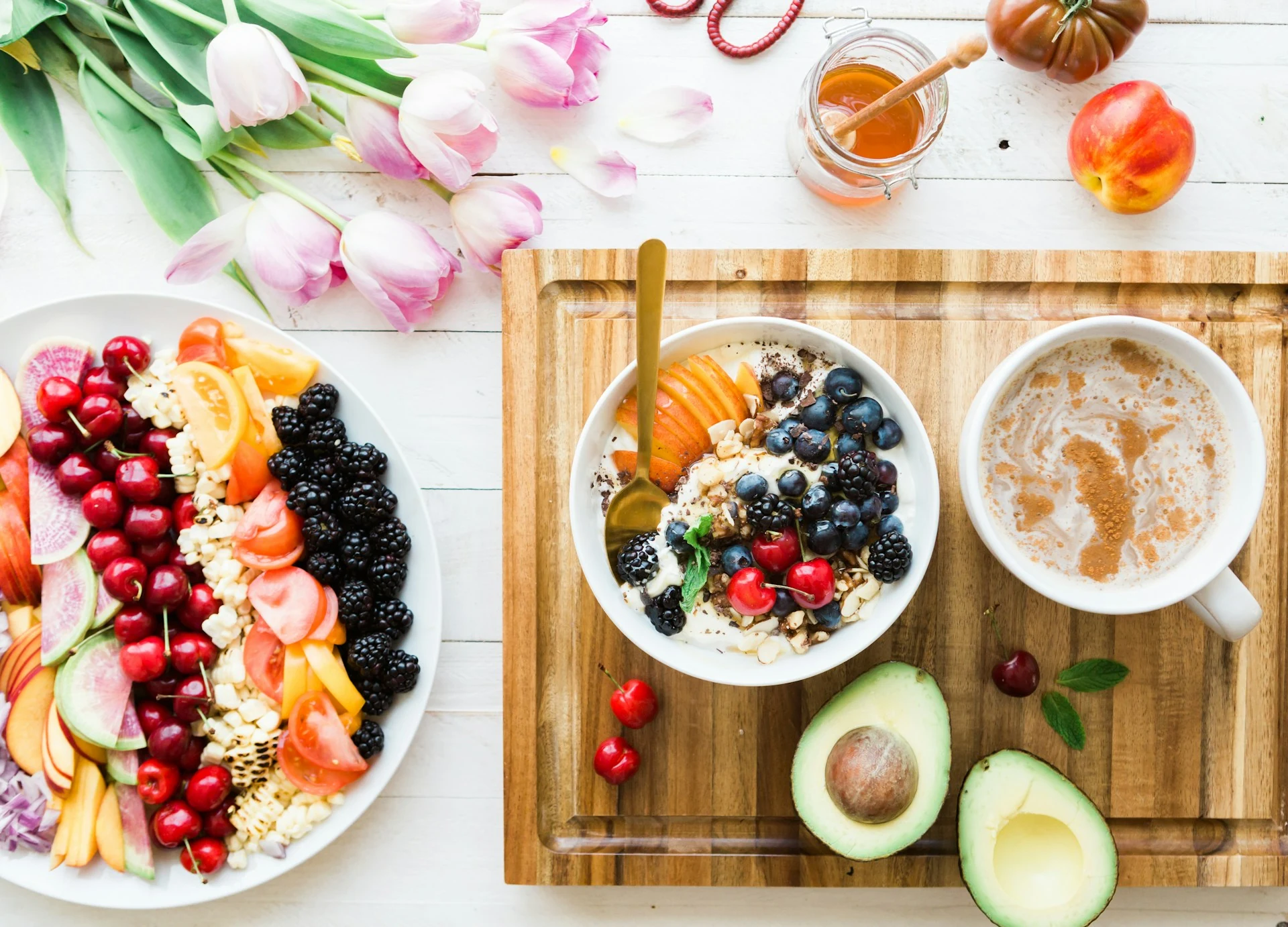 Fruit, a yogurt bowl, avocado and coffee on a breakfast table