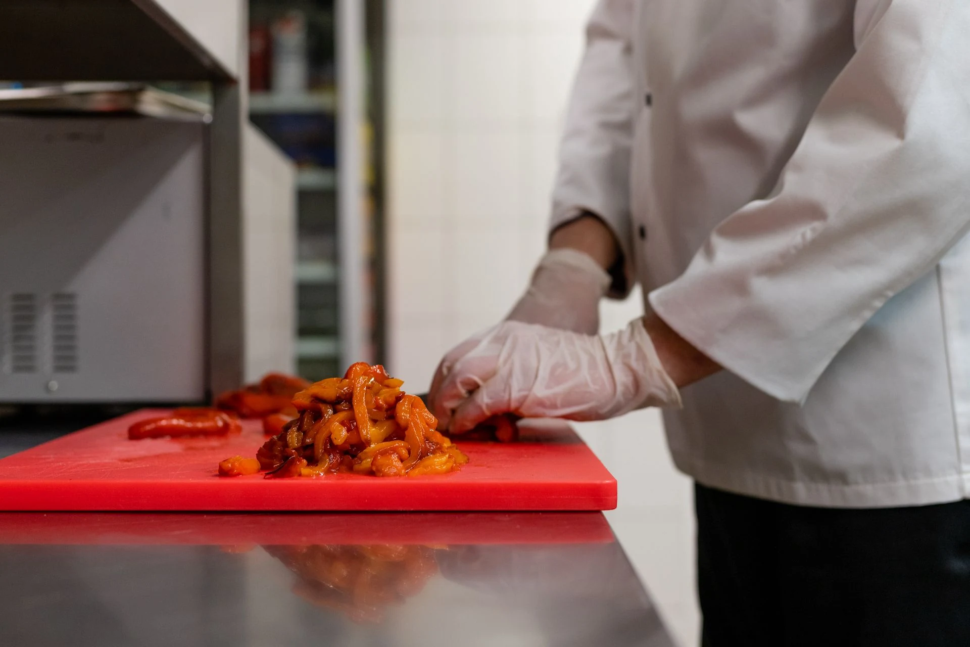 A chef slicing peppers on a cutting board in a professional kitchen