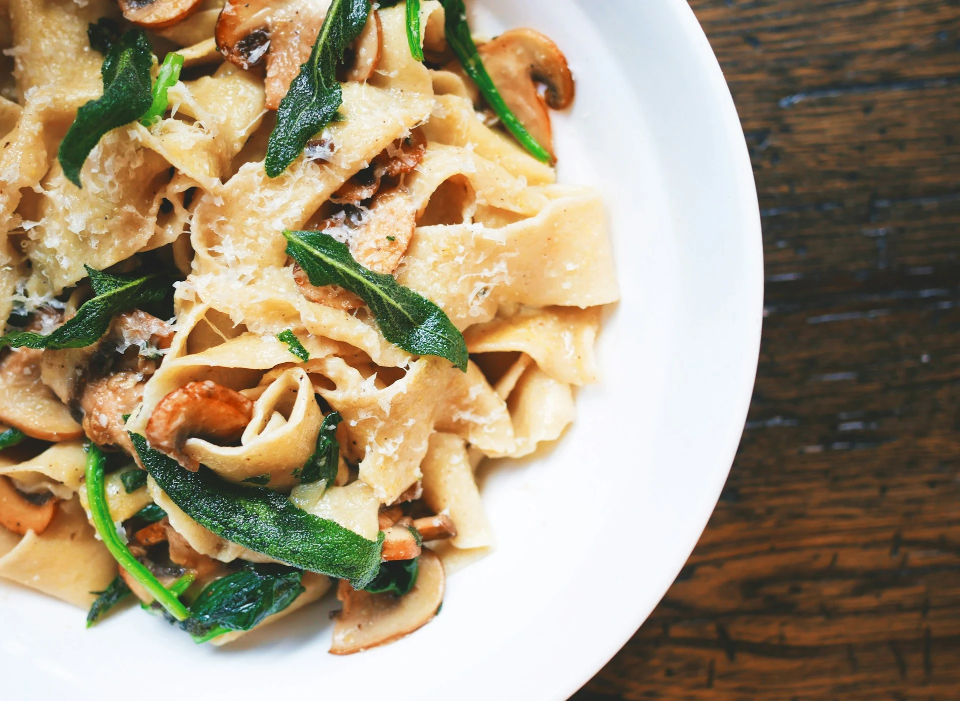 Pasta with mushrooms, herbs and cheese on a white plate