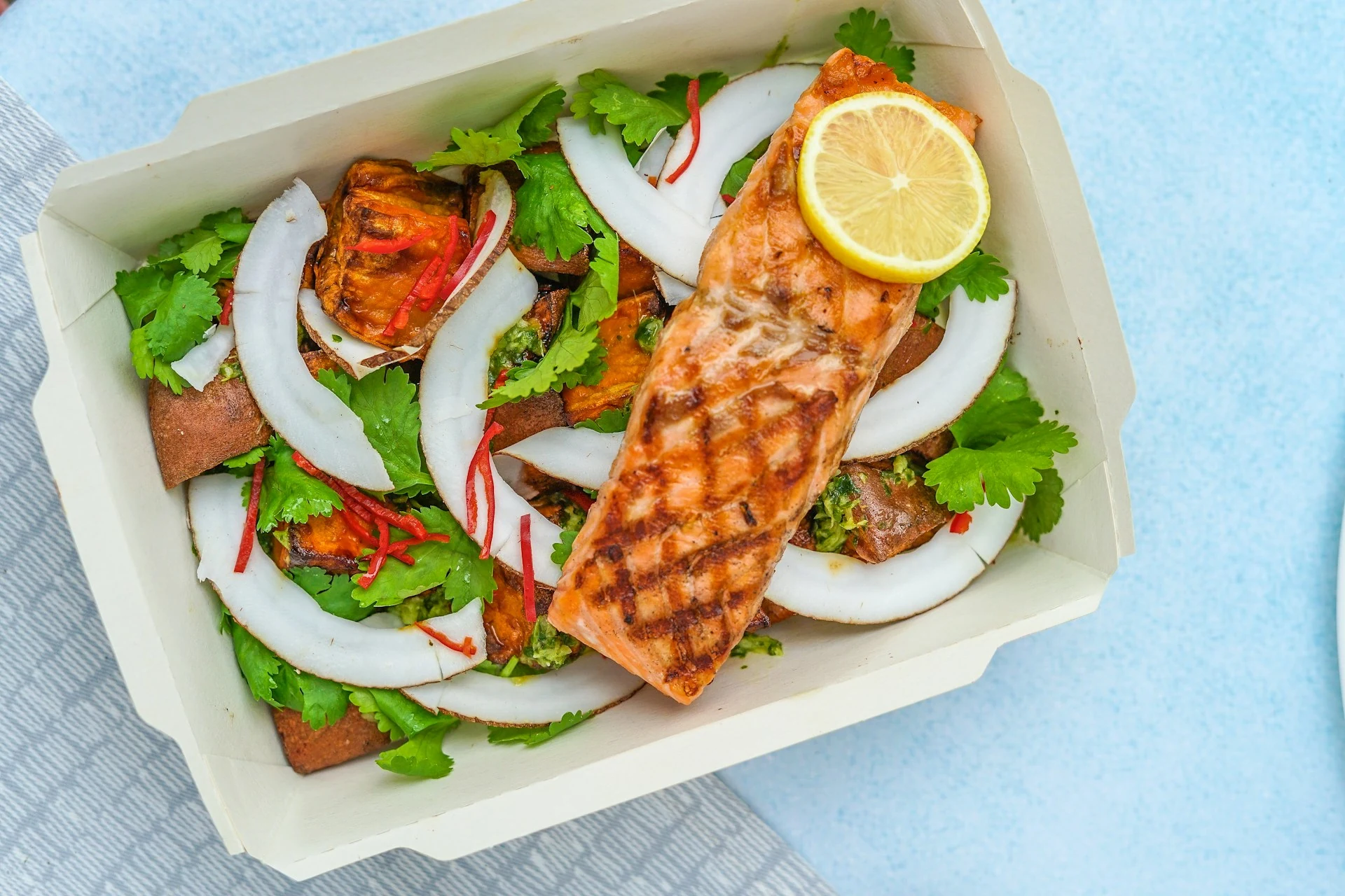 Grilled salmon, lemon and vegetables in a takeaway container
