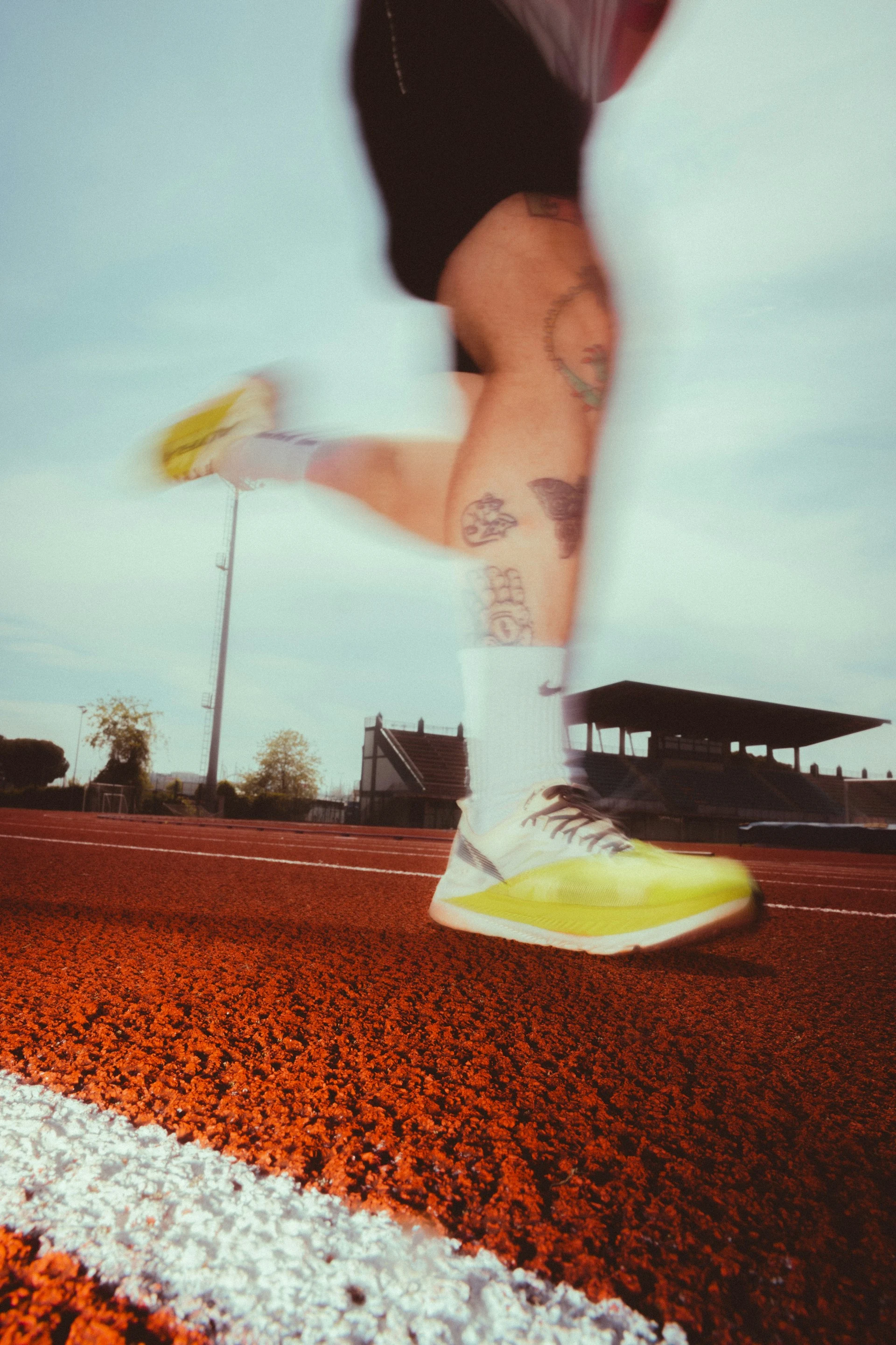 A runner’s legs and bright shoes in motion on a red track