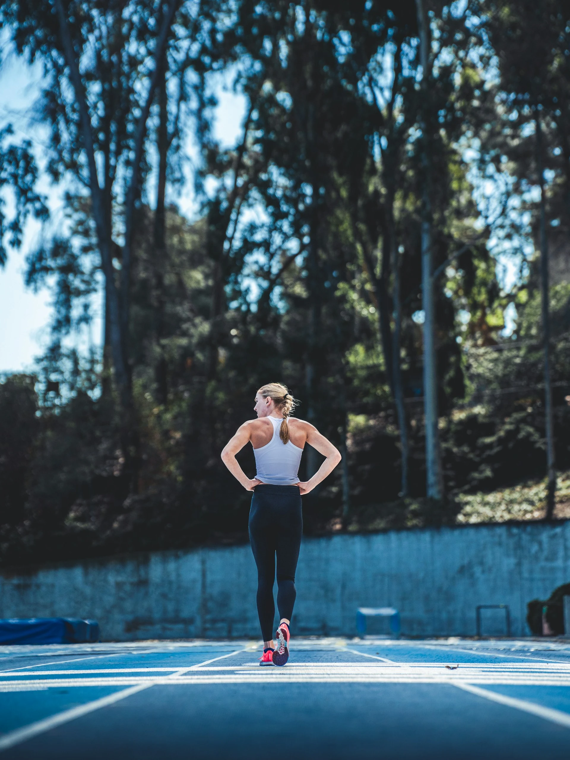 Runner on a blue outdoor track beneath trees